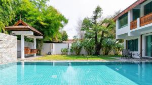 a swimming pool in front of a house at 提供免费汽车使用的含泳池被墅房间 in Chiang Mai
