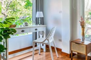 a desk and a chair in a room with a window at 提供免费汽车使用的含泳池被墅房间 in Chiang Mai
