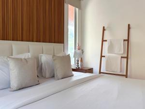 a large white bed with white pillows and a window at 提供免费汽车使用的含泳池被墅房间 in Chiang Mai