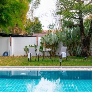 a patio with a table and chairs next to a pool at 提供免费汽车使用的含泳池被墅房间 in Chiang Mai
