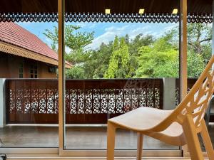 a chair sitting on a balcony with a window at 提供免费汽车使用的含泳池被墅房间 in Chiang Mai