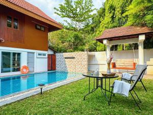 a patio with a table and chairs next to a pool at 提供免费汽车使用的含泳池被墅房间 in Chiang Mai