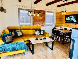 a living room with a yellow couch and a table at Romantické chalúpky Raj-Borievka, Čučoriedka a Drienka in Hrabušice