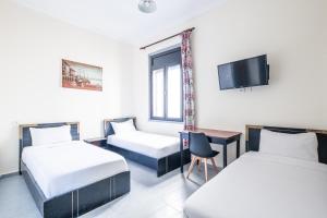 丹吉尔Hotel Mauritania的一间有两张床和一台电视的酒店房间