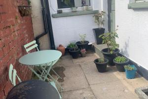 a patio with a table and a bunch of potted plants at Sleeps 7 Home Blackpool w Free Parking BBq WiFi in Blackpool