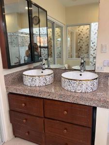 two sinks in a bathroom with two mirrors at DC Travellers Inn in Malolos