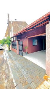 um prédio vermelho com uma calçada ao lado de um estacionamento em Cantinho Aconchegante in Foz em Foz do Iguaçu