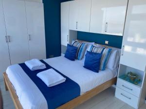a bedroom with a large bed with blue walls and white cabinets at Stunning Sea View Apartment in Newquay with a Pool in Crantock +5 photos