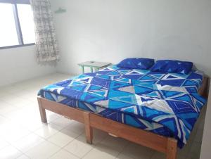 a bed in a bedroom with a blue and white quilt at Hotel Dahlia in Mantaak