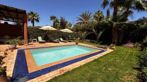 a swimming pool in a yard with palm trees at Dar Nadim sur le Golf de Samanah in Marrakesh