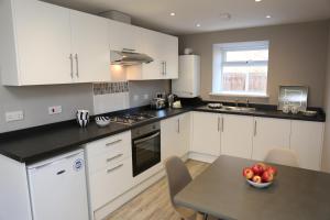 a kitchen with white cabinets and a table with a bowl of apples at Coach House 2 in St Asaph +13 photos