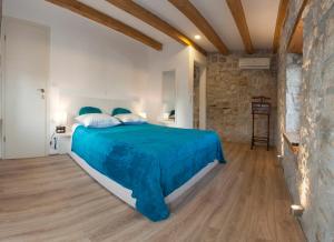 a bedroom with a bed with blue sheets and a stone wall at Villa Veli Varos in Split