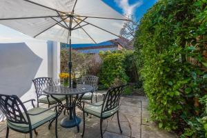 a table and chairs with an umbrella on a patio at Strand Cottage - Sheringham - Crabpot Cottages Sheringham in Sheringham
