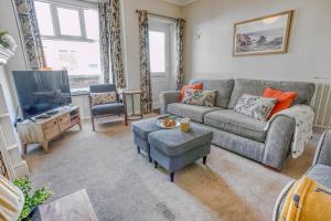 a living room with a couch and a tv at Strand Cottage - Sheringham - Crabpot Cottages Sheringham in Sheringham