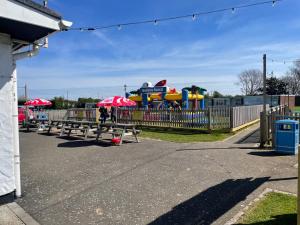 a group of picnic tables in front of a playground at 2-Bed Seaside Retreat - Sleeps 4 & Parking in Great Yarmouth