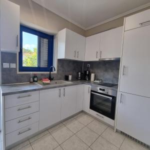 a kitchen with white cabinets and a window at Vaios Luxury Apartments Polichrono in Polykhrono