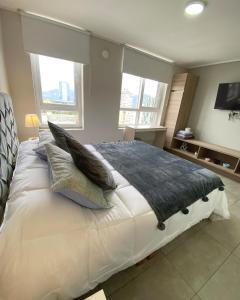 une chambre avec un grand lit blanc avec des oreillers dans l'établissement Cómodo departamento en el centro de Temuco, à Temuco