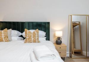 ein Schlafzimmer mit einem großen weißen Bett mit gestreiften Kissen in der Unterkunft Arlington Apartments - City Centre Luxury Apartments in Glasgow