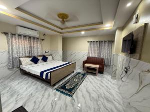 コルカタにあるOmshanti Guest House A Boutique Hotelのベッドとテレビと椅子のある寝室 +30枚の写真