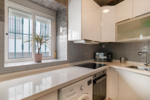 a kitchen with white cabinets and a sink and a window at Casa Buganvilla in Barbate