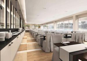 restauracja z białymi krzesłami, stołami i oknami w obiekcie Baltic Inn w Pogorzelicy