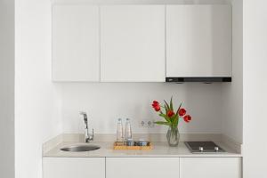 a kitchen with a sink and a vase of red flowers at Mariinsky Boutique Hotel in Batumi