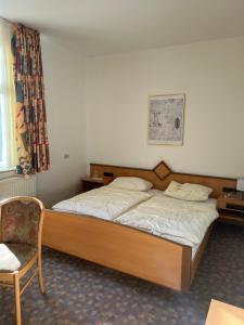 a bedroom with a wooden bed with a chair and a window at Königszinnenberg Hotel in Bodenwerder