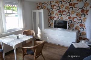 Bungalow Robbe im Ostseeidyll am Waldrand في أوستسيباد نينهاجن: غرفة معيشة مع طاولة وتلفزيون