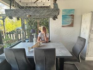 a woman sitting at a table in a restaurant at Lichtdurchflutetes Traumhaus 800 Meter zum Strandaufgang, uneinsehbarer Garten mit Terrassenüberdachung, hundefreundlich in Sint Maartenszee +40 photos