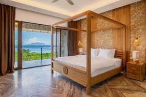 a bedroom with a canopy bed with a view of the ocean at Gardens Hill Resort & Spa in Beau Vallon +67 photos