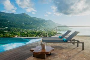 un banc assis sur une terrasse à côté d'une piscine dans l'établissement Gardens Hill Resort & Spa, à Beau Vallon