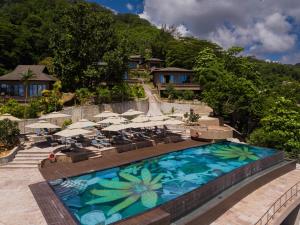 une piscine avec des parasols et des chaises et un complexe dans l'établissement Gardens Hill Resort & Spa, à Beau Vallon