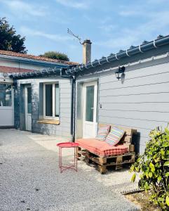 a bench with two pillows sitting next to a building at La Maison au fond du jardin - proche centre ville in Le Mans