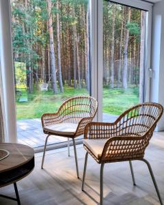 2 Stühle und ein Tisch vor einem Fenster in der Unterkunft Vila MurMur Papėje in Pape