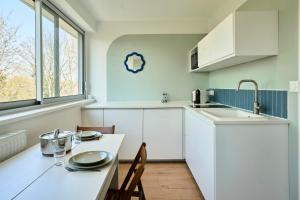 a kitchen with white cabinets and a table with chairs at Le Nid - Parking - 15 min centre de Lille in Wasquehal