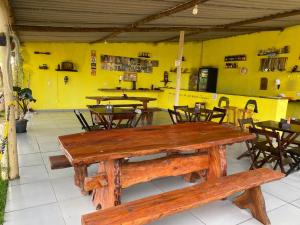 a restaurant with wooden tables and chairs and yellow walls at Pousada Sitio do Terrão a 500 metros da BR 040 e a 10 minutos da Prainha in Três Marias