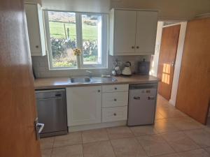 a kitchen with white cabinets and a sink and a window at Cooley House in Grange Cross