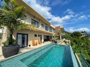 a villa with a swimming pool in front of a building at Maluhia Ilhabela 4 in Ilhabela
