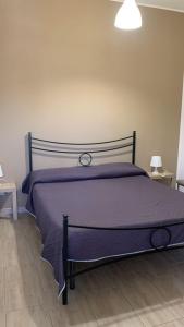 a purple bed in a room with two tables at Home Apollo in Giardini Naxos