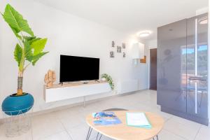 een woonkamer met een tv aan een witte muur bij Appartement Azur et Lavande in Fréjus