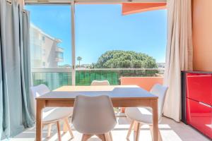 Un comedor con mesa y sillas y una gran ventana. en Appartement Azur et Lavande, en Fréjus
