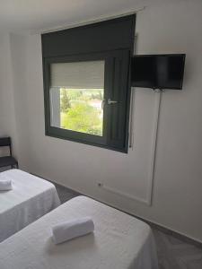 a mirror in a room with two beds and a window at Hotel l'Albera in La Jonquera