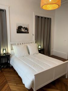 a bedroom with a large white bed with two tables at Appartement #2 cœur de ville in Le Mans