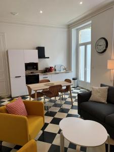 a living room with couches and tables and a kitchen at Appartement #2 cœur de ville in Le Mans