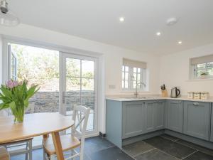 a kitchen with gray cabinets and a table and a dining room at Sunrise Cottage in Bodmin