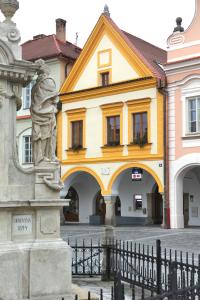 a yellow building with a statue in front of it at Apartmány Reve in Třeboň