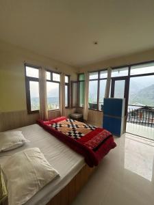 ein großes Bett in einem Zimmer mit Fenstern in der Unterkunft Bodh Niwas -A unit of The Nest Community in Vashisht