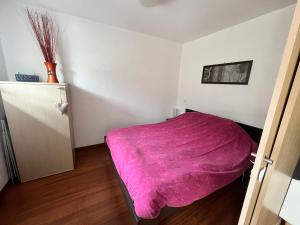 a small bedroom with a pink blanket on a bed at Les chalets du verdon in Allos