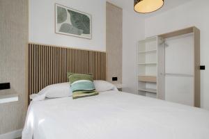 ein Schlafzimmer mit einem weißen Bett und einem grünen Kissen in der Unterkunft Apartamentos Habana 3 in Barbate