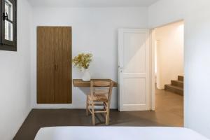 a bedroom with a table and a chair and a door at Acron Villas Paros in Kolympithres